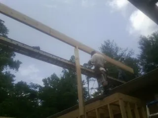 Carpenter setting a ridge beam over a new addition frame — Ice Dam Removal by Roofing Brothers in Petal
