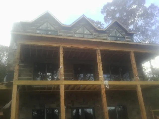Dormers and porch framing on a large log home under construction — Roof Coating work by our crew in Petal