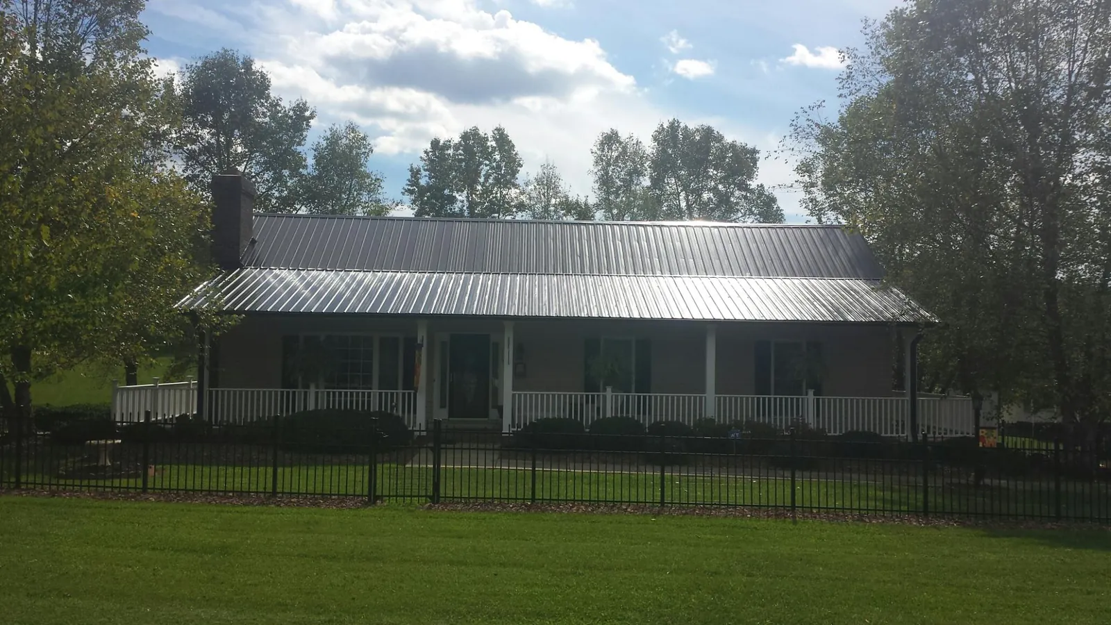 Gray metal roof on a brick ranch with a full width front porch — Gutter Guard Installation work by our crew in Petal
