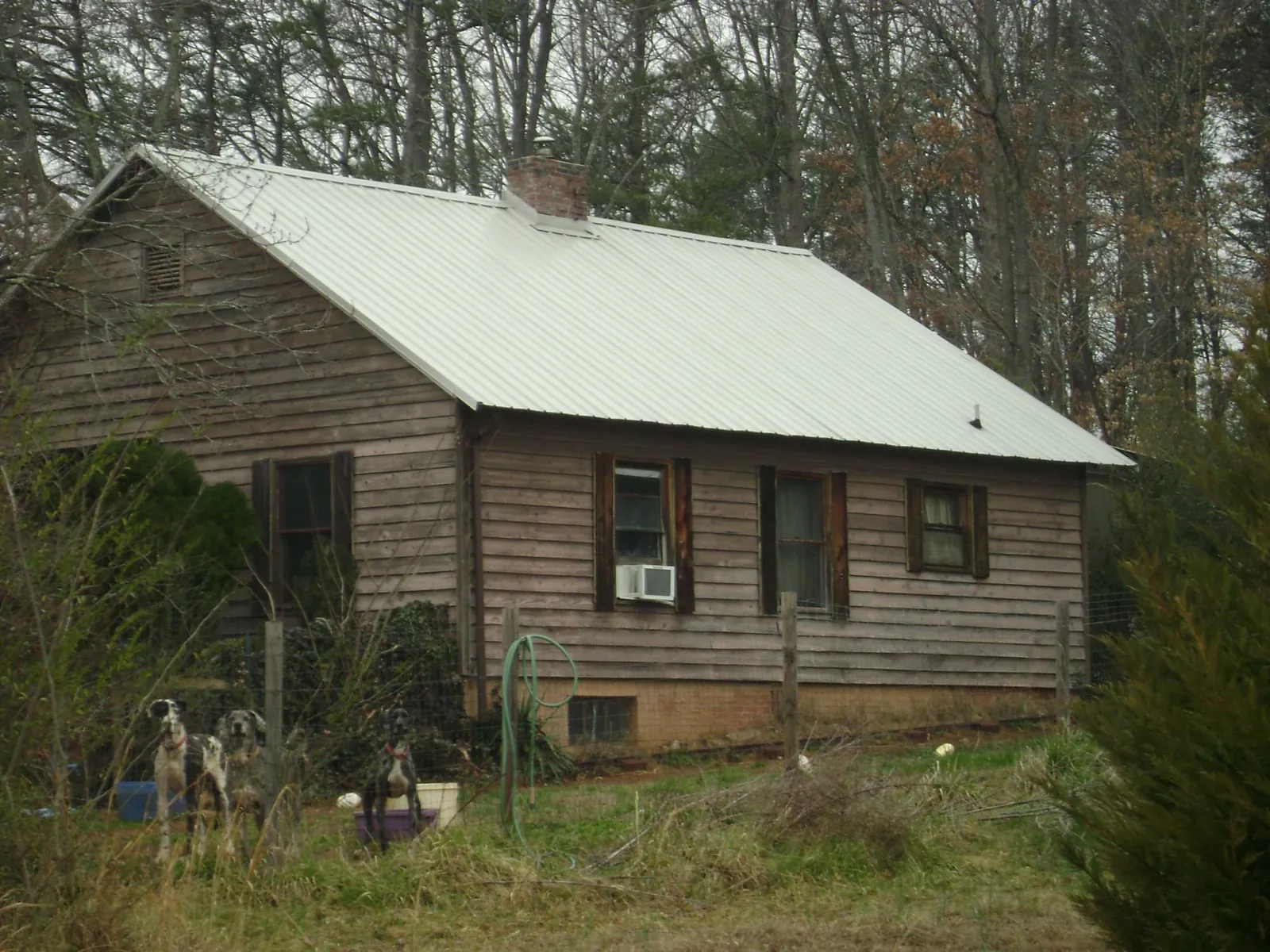 White metal roof on an old wood sided farmhouse, from a Metal Roof Installation job in Petal