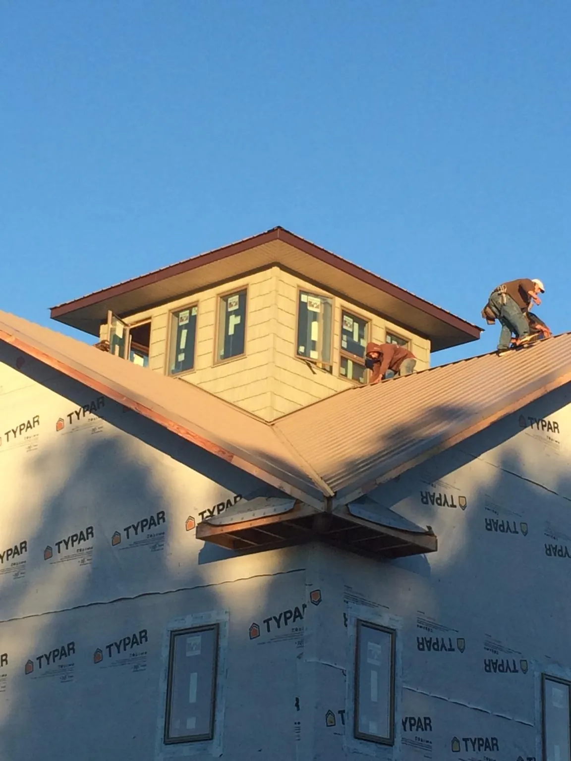 Roofers working around a rooftop cupola on a new metal roof at sunset — Roof Waterproofing in Petal by Roofing Brothers